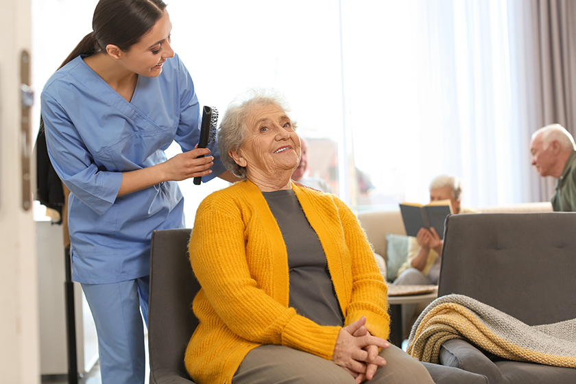 Care worker brushing elderly woman in geriatric hospice 